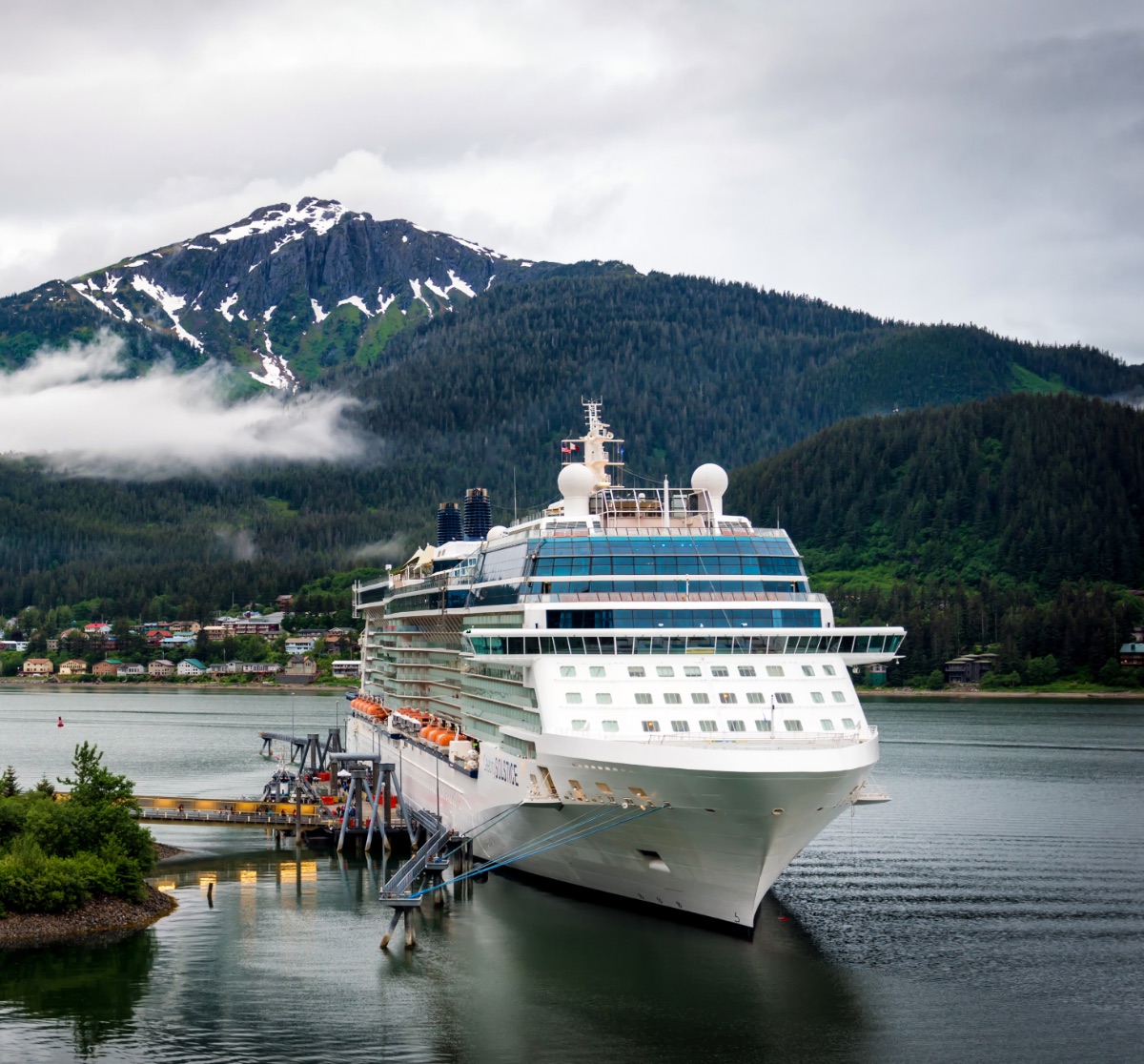 Large passenger ship docked beneath snow-capped mountains